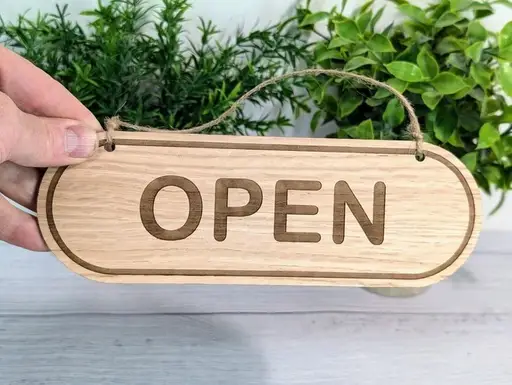 تابلو چوب روشن با نوشته OPEN و حاشیه کپسولی حک‌شده و بند آویز