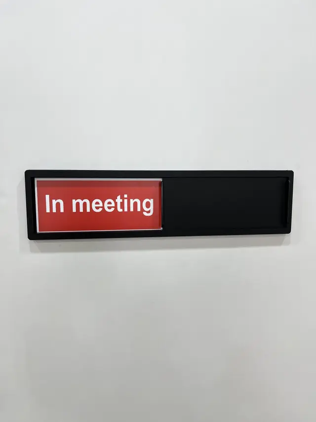 تابلو کشویی مشکی در حالت قرمز In meeting کنار در اتاق